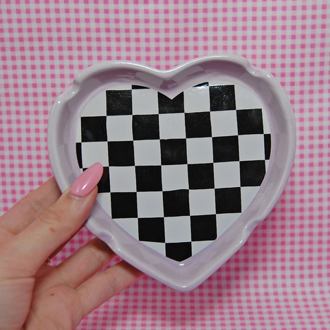 Handcrafted ceramic ashtray in a checkerboard print with a lavender border. It measures 5.25 inches long, 5 inches wide, and 1 inch deep.