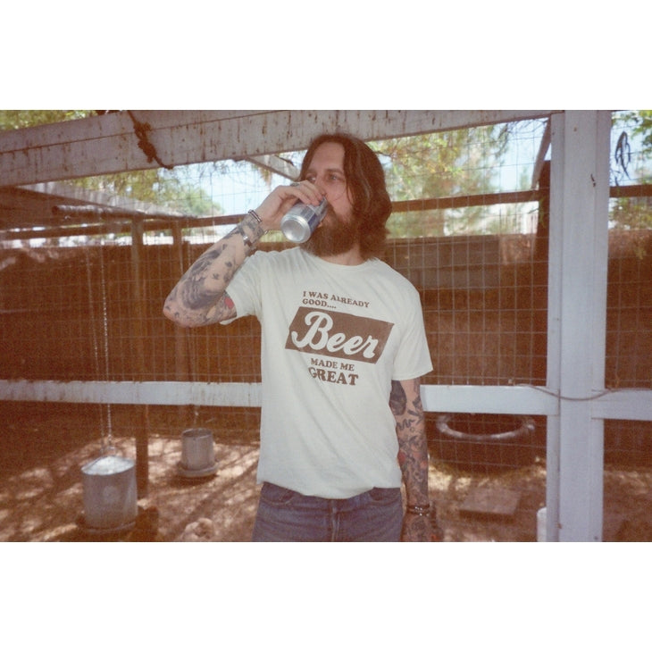 Off-white/light cream colored t-shirt with the words "I was already good... Beer made me GREAT!" printed in a vintage brown font. The shirt is made from 100% pre-shrunk cotton and has a relaxed fit.  It features a vintage wash for a worn-in appearance.